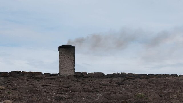 Laeso, Denmark A wood burning chimney on a thatched roof with smoke used to make salt in the salt flats.  