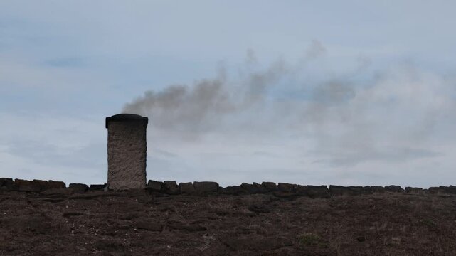 Laeso, Denmark A wood burning chimney on a thatched roof with smoke used to make salt in the salt flats.  