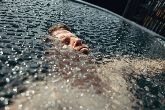 A cold recovery scene shows a man submerged in an ice bath outdoors.