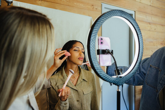Content creator receiving makeup application during studio photoshoot with professional lighting
