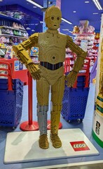 Fototapeta premium Enorme figura de exposición del robot C-3PO de Star Wars, construido con ladrillos de Lego, en la entrada de una juguetería Juguettos de Madrid, España, 3 de junio de 2026