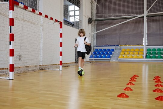 Teenage boy kicking ball while spending time together at home
