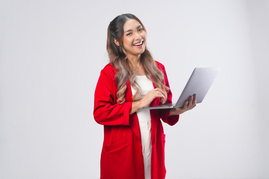 Smiling young Asian woman wearing red jacket holding laptop to work or browsing.