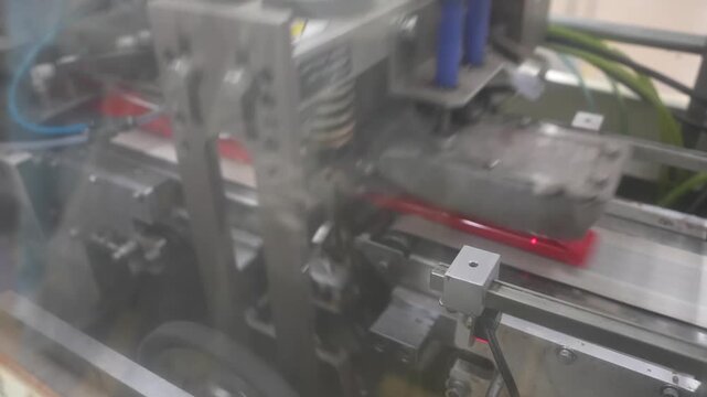 Close view of a high speed sealing machine forming wrapped portions inside a guarded enclosure