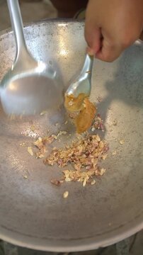 Cooking Thai sweet and savory crispy small fish (Pla Krob Phad Krathiam). Deep-frying tiny dried anchovies until golden crispy, sauteing minced garlic, palm sugar, and seasoning in a wok to form a gla