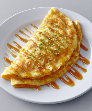 Golden layered pastry topped with honey and pistachio on a white plate. Sweet dessert presentation for bakery, restaurant menu, food editorial, and culinary concept.