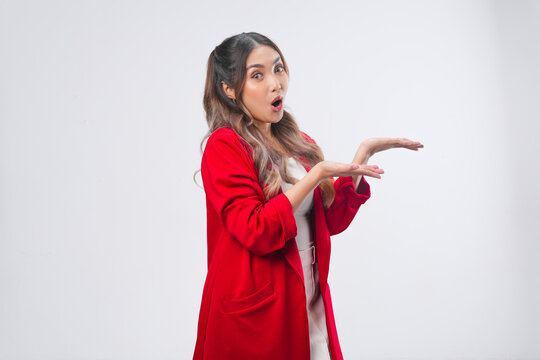 Shocked young Asian woman in a red jacket is presenting the copy space beside her.