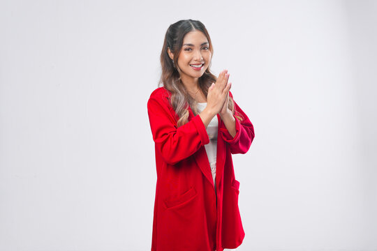 Peaceful young Asian woman in a red jacket is gesturing greeting or namaste.