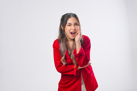 Pretty young Asian woman is shouting or whispering with hands on her mouth.