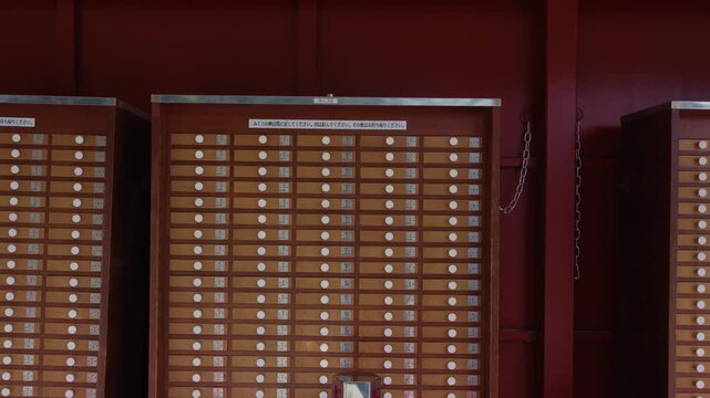 Rows of wooden omikuji fortune drawers with kanji labels at a temple in Tokyo Japan