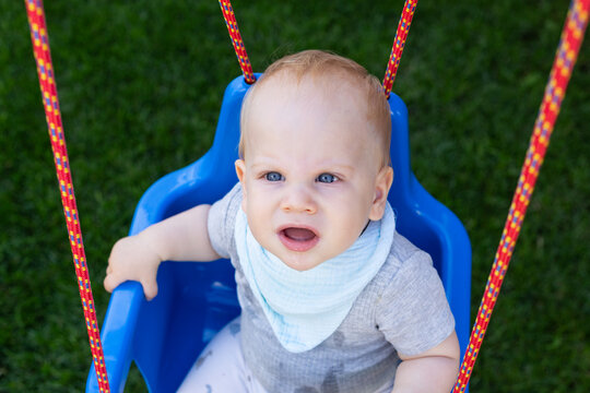 Curious Baby Sitting in a Blue Outdoor Swing
