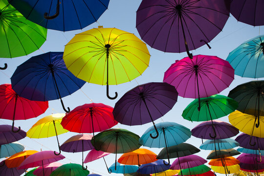 Rows of colorful umbrellas create a vivid overhead display, outdoor street decoration, creative festival background, summer travel theme.