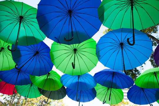 Green, blue, and turquoise umbrellas create a dense outdoor canopy, vibrant decorative installation, creative festival background.