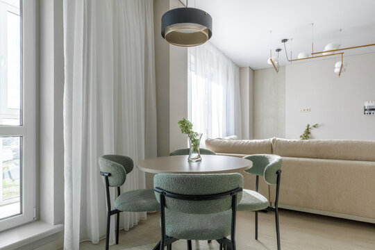 Modern Dining Area Interior with Round Table and Green Upholstered Chairs