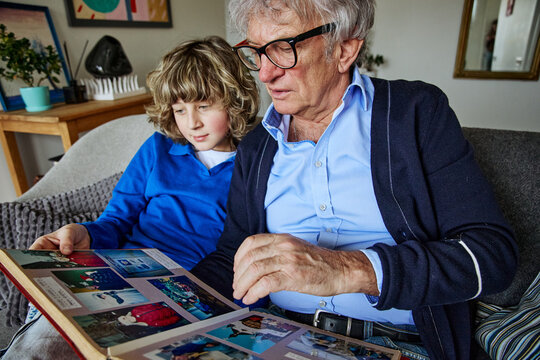 Senior man and teenage boy looking at photos while sharing a relaxed day at home