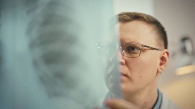 Examining the patient's lungs, a doctor studies a detailed x-ray in a clinical setting, using medical expertise to spot abnormalities and ensure accurate diagnosis for timely treatment