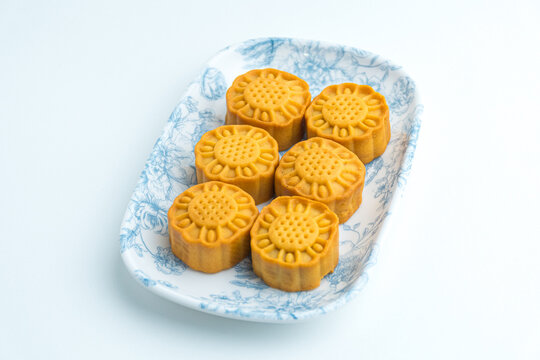 Traditional golden baked mooncakes arranged on a blue patterned ceramic plate isolated on white background