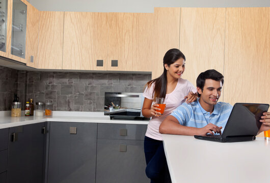 Smiling couple using laptop in kitchen