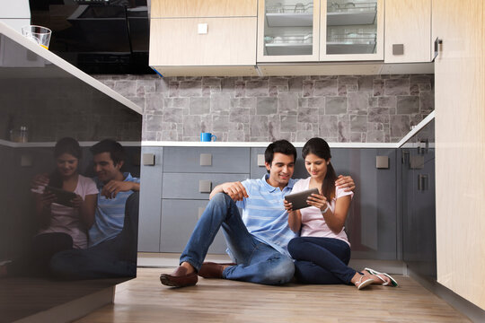 Full length of couple using digital tablet in kitchen