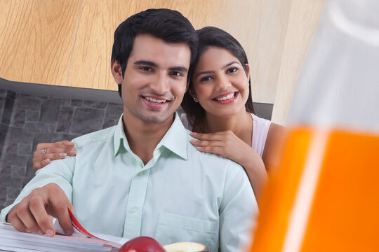 Portrait of happy couple with catalogues in kitchen