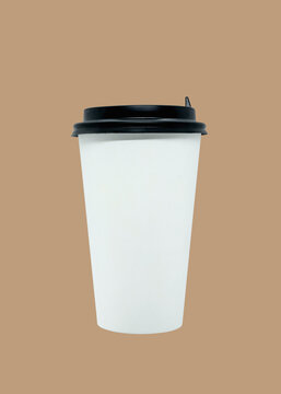 White disposable coffee cup with black lid isolated on beige background. Blank mockup template for creative design and branding projects.