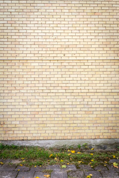 Yellow brick wall background with green grass. Architectural detail.