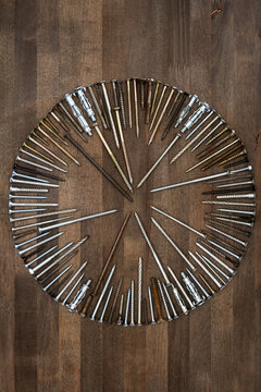 Circle made of various screws and nails on brown wood texture. Industrial flat lay. Carpentry still life.