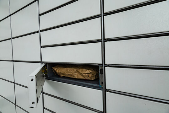A package in a white parcel locker. A concept for online shopping and logistics. Automated delivery and pickup of parcels. Poland