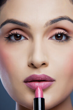 Portrait of an attractive female applying lipstick 