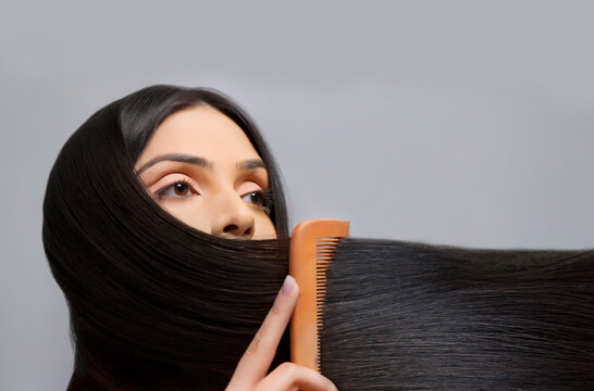 Young woman combing her beautiful long hair over colored background 