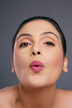 Portrait of a young female making a facial gesture over colored background 