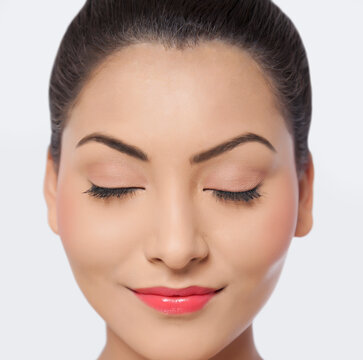 An attractive young woman with eyes closed smiling over white background 