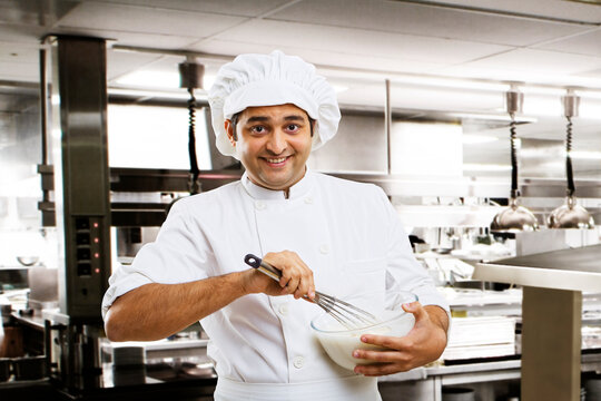 Chef beating dough in a bowl 
