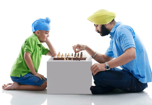 Sikh boy playing chess with his dad 