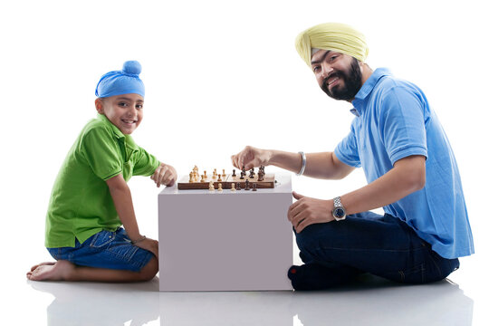 Sikh boy playing chess with his dad 