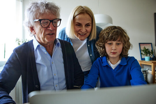 Three family members looking at an object in a bright and comfortable home interior