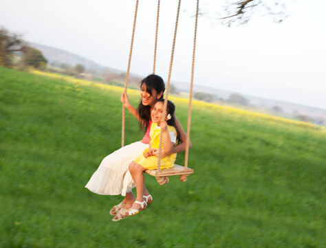 Mother and daughter having fun on a swing 