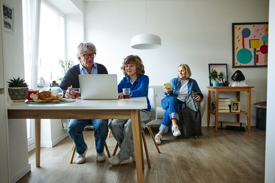 Three family members using laptop while spending time together at home