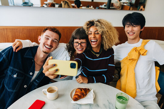 Friends taking a selfie laughing together in cafe