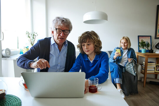 Three family members using laptop in a bright and comfortable home interior