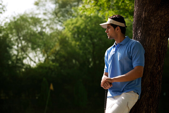 Golfer leaning against a tree 