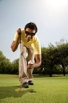 Man taking a golf ball out of a hole 
