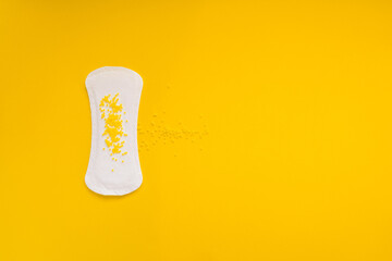  Sanitary Pad with Yellow Beads Symbolizing Urinary Leakage on Yellow Background © Mariya
