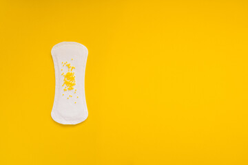  Sanitary Pad with Yellow Beads Symbolizing Urinary Leakage on Yellow Background © Mariya