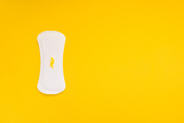 Sanitary Pad with Yellow Beads Symbolizing Urinary Leakage on Yellow Background © Mariya