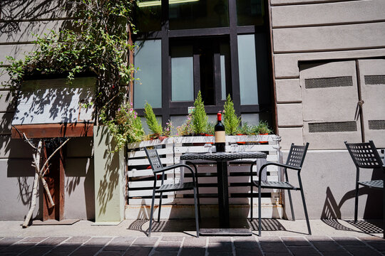 Outdoor Cafe Table with Wine Bottle in Urban Courtyard Setting