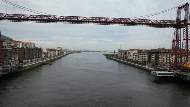 Aerial view of the historic Vizcaya Bridge spanning the Nervion River with urban buildings along the riverbanks in Portugalete, Basque Country, Spain.