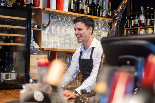Smiling Bartender Working Behind the Bar in a Restaurant