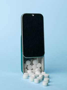 Open Metal Pill Box with White Tablets on Pastel Blue Background