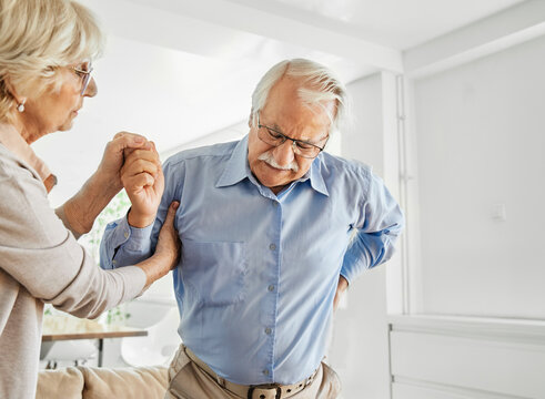 Elderly couple helpin each other standing up and walking, illness and recovery, backpain